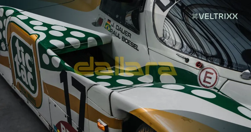 Close-up van een raceauto met Tic Tac-logo en groene stippen. Namen van coureurs J. Dauer en R. Boesel zichtbaar. Links staat "dallara".