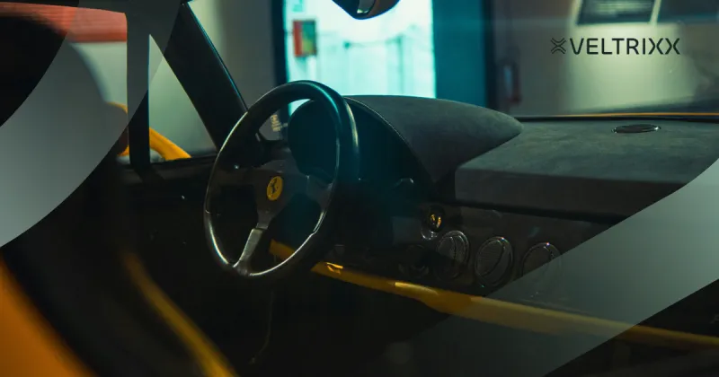 Close-up van een autostuur en dashboard in een donkere, sfeervolle setting, met logo van Veltrixx op de achtergrond.